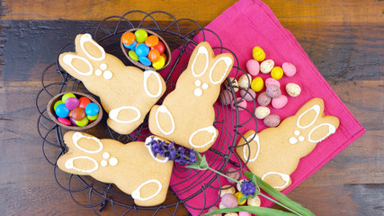 Happy Easter overhead with Easter Bunny cookies and decorations on a wood table background