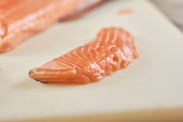 Piece of raw salmon. Little piece of fresh salmon fish on white cutting board. Restaurant of seafood.
