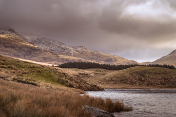 View across the lake to the Snowdon Horseshoe at Llyn y Dywarchen, as the sun light breaks over the mountain side in the Snowdonia National Park, Wales.