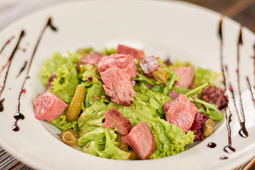 Delicious salad with lettuce and beef. Green salad with veal meat, cornichons and mustard. Delicious and healthy food. Lunch time at restaurant.