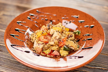 Appetizing salad served with sauce. Delicious salad with barbecued vegetables and chicken. Tasty dinner on plate.