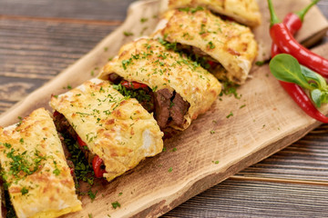 Delicious burrito with meat, beans and vegetables. Appetizing mexican burrito on wooden board in restaurant. Restaurant of mexican food.