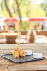 Crispy shrimps on blurred background. Delicious appetizer with sauce on plate. Spicy dish in restaurant.