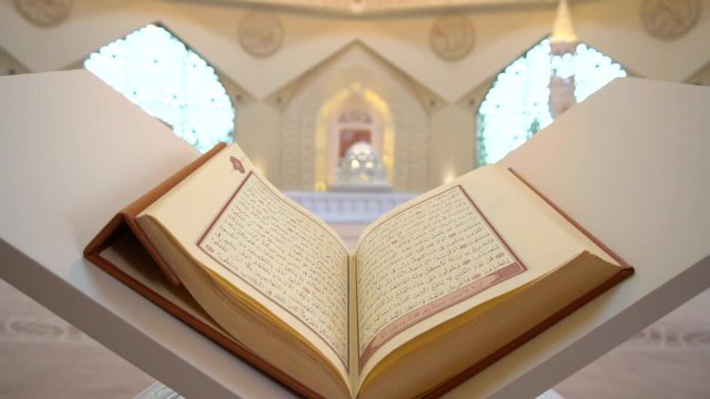 A man is reading Quran on the reading desk in a mosque.