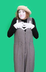 The mime girl dressed in black and white  shows bright emotion performing a show, isolated on green