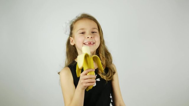 Curly cheerful girl holding a banana as a microphone. 