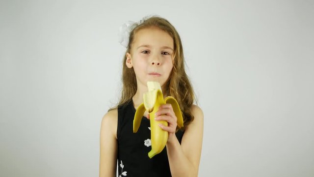 Curly girl eating a banana on a white background.