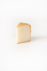 Slice of Italian or French hard cheese on white backgrund