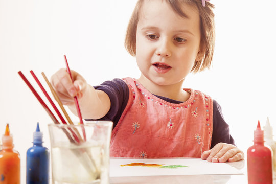 Сute little girl learns to paint as the most powerful investment in successful future. Creativity, education, success concept.