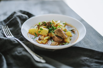 Irish beef stew with fresh parsley on a dark wooden background in natural light