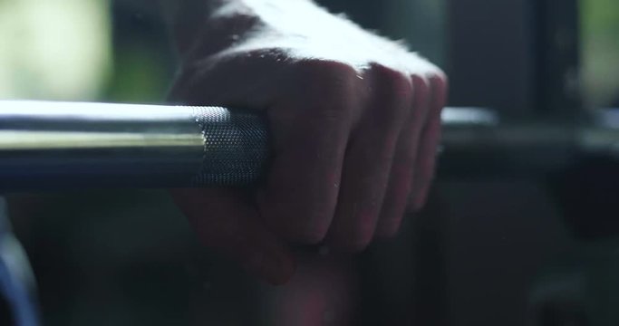 Close up of a hand of a man grabbing an Olympic rocker for training at the gym, and preparing for professional competitions. Concept of: sport, power, muscles, determination.
