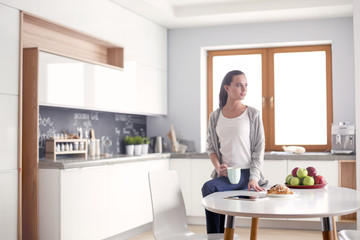 Obraz premium Happy woman drinking tea in the kitchen at home.