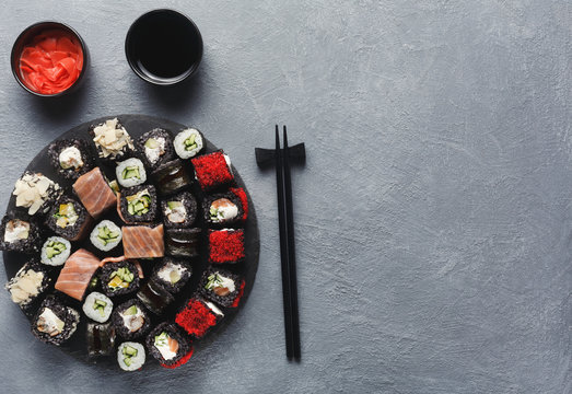 Set of black rolls with chopsticks on gray table