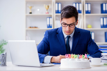 Young businessman celebrating birthday alone in office