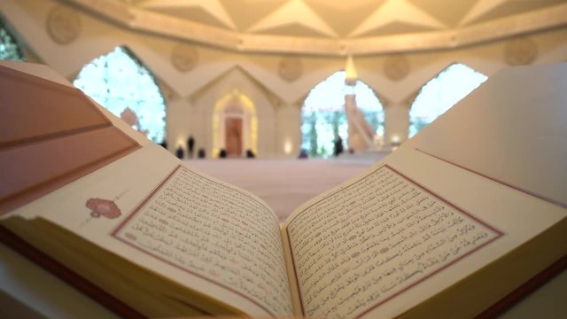 A man is reading Quran on the reading desk in a mosque.
