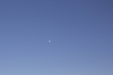 View of half moon with clear blue sky background.