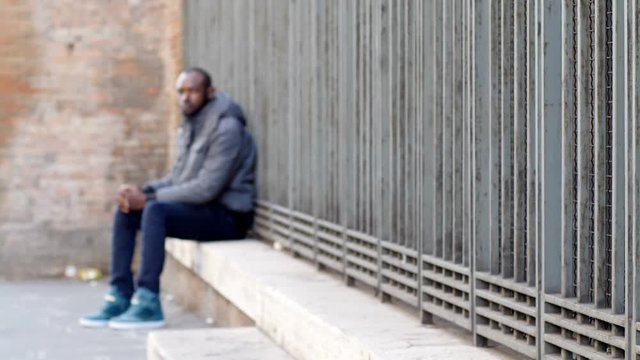 black immigrant alone in the street: loneliness, poverty, misery