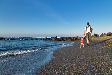 Father and baby daughter walking at thel beach