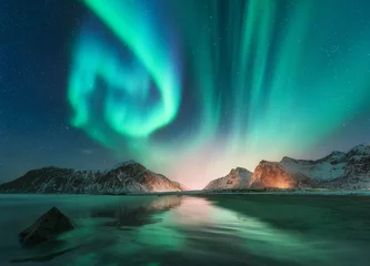 Fotobehang Noorderlicht Aurora borealis in Lofoten-eilanden, Noorwegen. Aurora. Groen noorderlicht. Sterrenhemel met poollicht. Nacht winterlandschap met aurora, zee met luchtreflectie, stenen, strand en besneeuwde bergen