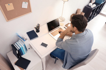 Young man working with laptop at table in office