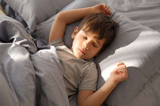 Cute little boy sleeping in bed at home
