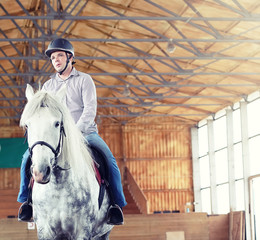 People on a horse training in a wooden arena
