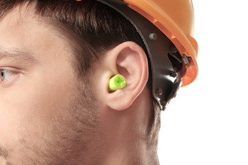 Male worker with earplug on white background. Hearing protection equipment