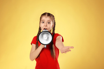 Obraz premium Emotional little girl with megaphone on color background