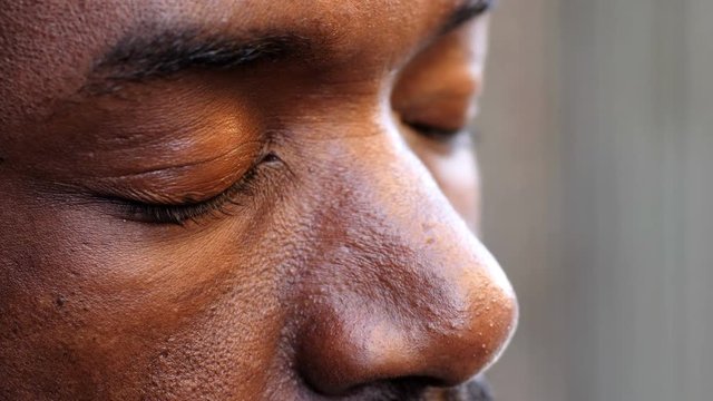 eyes of a black man closing in prayer- macro