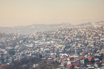 Aerial view of the hills of the suburbs of Sarajevo, Bosnia and Herzegovina during a cold winter afternoon snow covering everything. A mosque can be seen in front