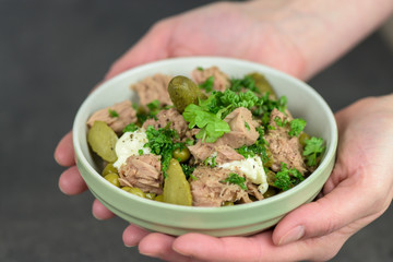 A hands holding a bowl of healthy tuna salad - closeup