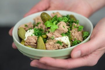 A hands holding a bowl of healthy tuna salad - closeup