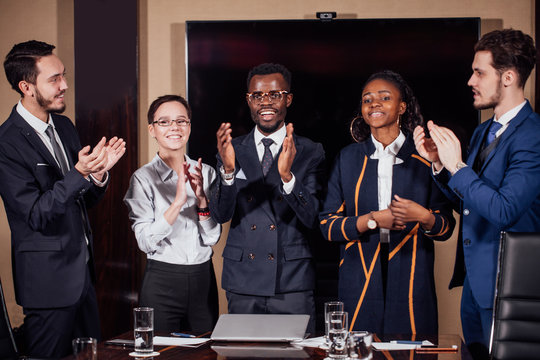 Professional multiracial business team applauding in meeting room