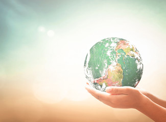 Earth day concept: Human hands holding earth global over blurred green nature background. Elements of this image furnished by NASA