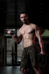Obraz na płótnie Canvas Geek Man With Dumbbell Exercising Biceps