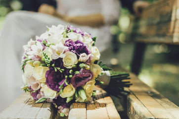 wedding bouquet of beige white violet flowers on the bench