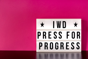 International Women's Day - concept - 'Press for Progress' 2018 theme  - light box with cinema style lettering on hot pink background with copy space