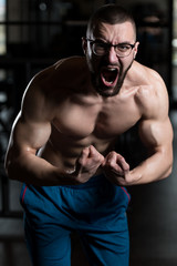 Obraz na płótnie Canvas Young Bodybuilder Wearing Eyeglasses Flexing Muscles