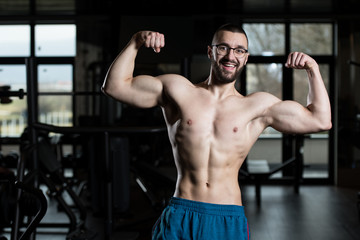 Fototapeta na wymiar Young Bodybuilder Wearing Eyeglasses Flexing Muscles