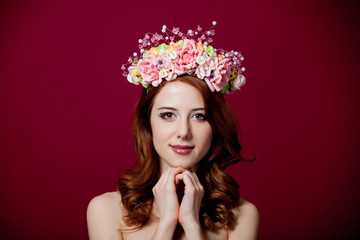 Naklejka premium Young redhead girl with wreath on red background