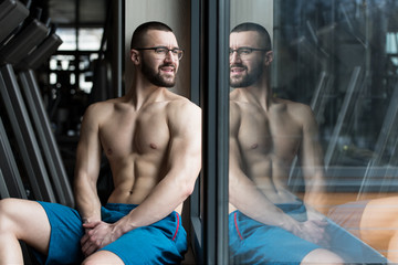 Fototapeta na wymiar Muscular Man After Exercise Resting In Gym