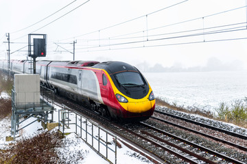 Fototapeta premium Cloudy foggy winter day view of Train on UK Railroad in England. Emma storm railway landscape.