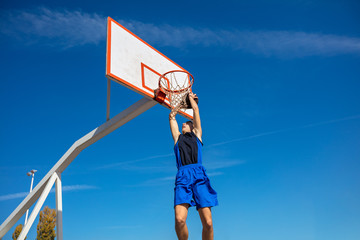 Young Basketball street player making slam dunk