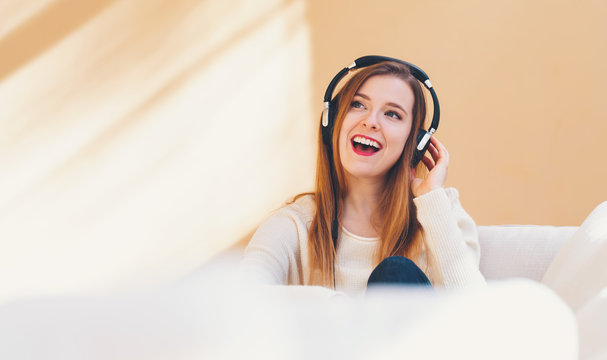 Happy Young Woman Listening To Music On Headphones At Home