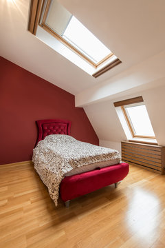 Bedroom interior in luxury red loft, attic, apartment with roof windows