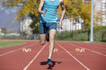 Obraz premium Man runner in blue shirt and shorts and sport shoes in steady position before run at start of race.