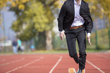 Young businessman in suit running on track