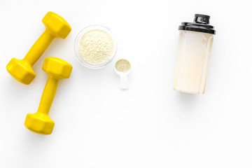 Nutrition for muscle growth. Scoop of protein near shaker and dumbbell on white background top view copy space