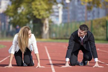 Close up of 20 year old businessmen and businesswoman ready to run at start point.
