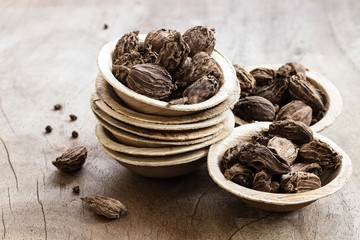 Black cardamom in bowls on wooden background